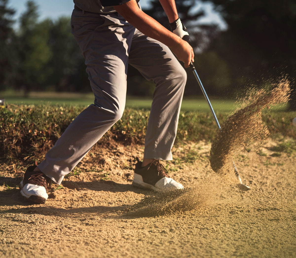 person hitting golf ball out of the sand