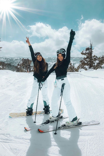 two girls posing for a picture on skis