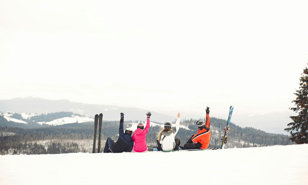 Skiers with hands up sitting on a mountain