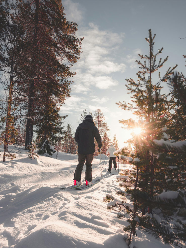 Skiers on a mountain trail with sunset in background