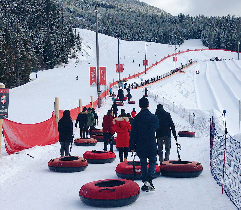 people taking snow tubes up a hill